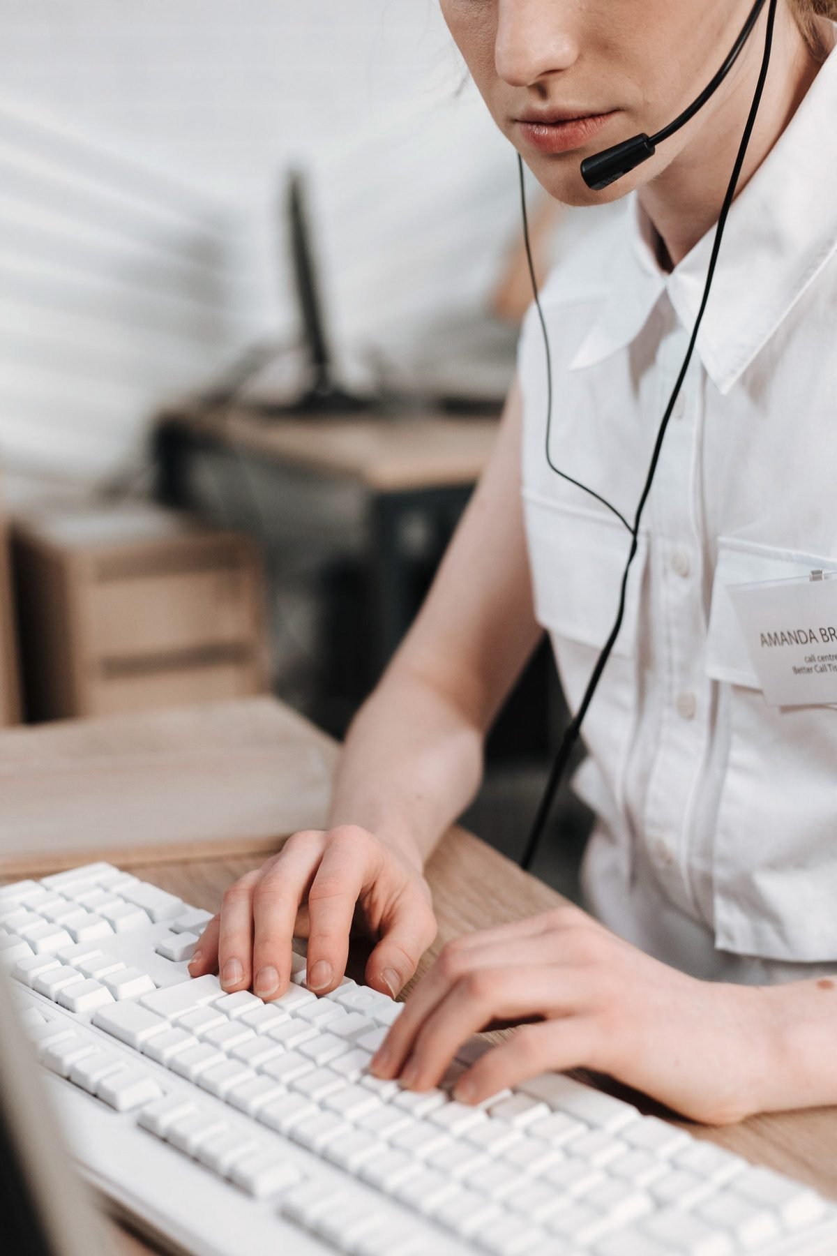 An operator types a caller's details into a computer while listening through a headset.