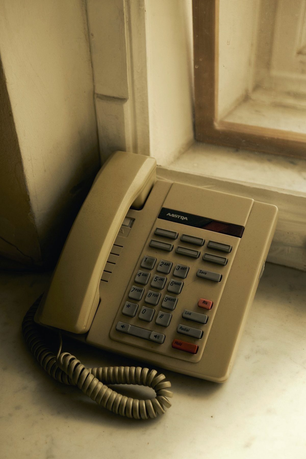 A beige corded landline telephone on a sill.