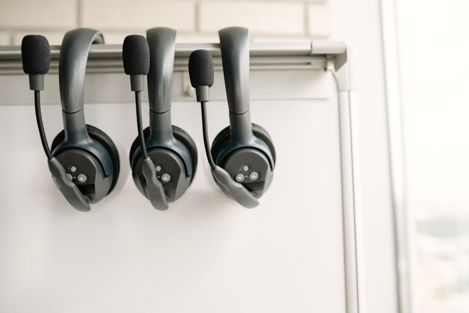 Three headsets hang ready on a wall hook.