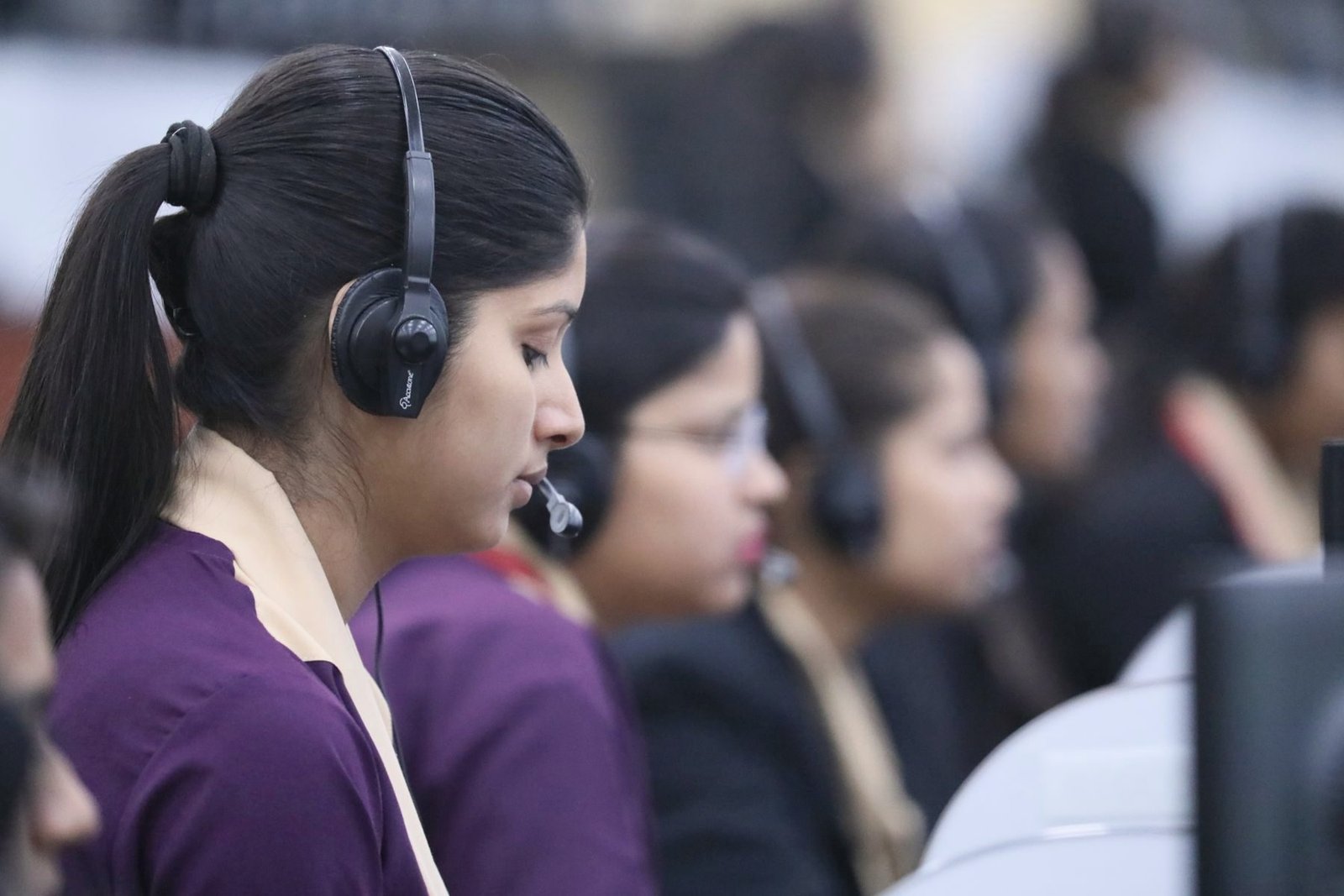 An operator in profile concentrates on a call through her headset.